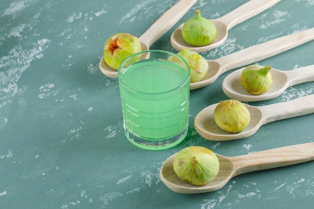 Бесплатное фото Зеленые смоквы с питьем в деревянных ложках на стене гипсолита, взгляд сверху.