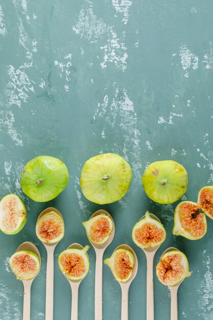 Green figs in wooden spoons on a plaster wall. top view.