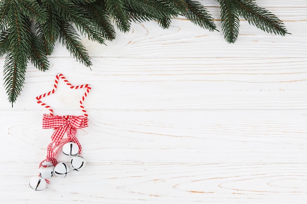 Green fir tree branches with jingle bells on table 