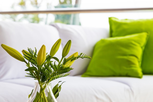 Green flowers as interior decor and a white sofa with green pillows