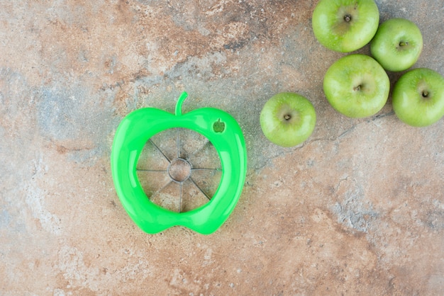 Green fresh apples with peeling tool on marble table.