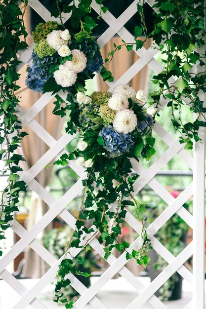 白と青の花の緑の花輪が壁にぶら下がっています