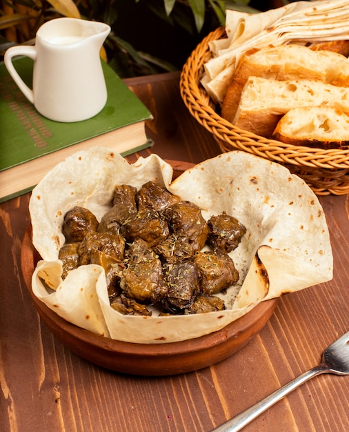 青ぶどうの葉に肉、米、ハーブ、タマネギを詰め、オリーブオイルで調理し、ラバッシュとパンを添えて。