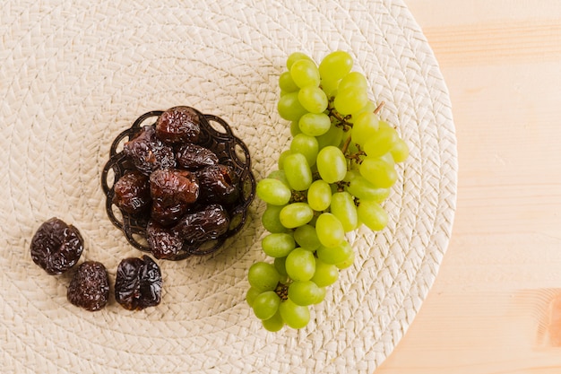 Free photo green grape near prunes on saucer