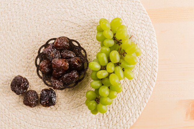 Green grape near prunes on saucer