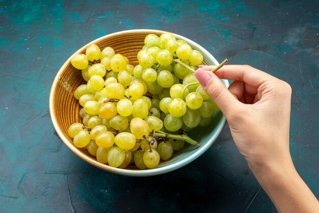 зеленый виноград внутри тарелки берет женщина на темном фоне фруктовое свежее вино спелый сок