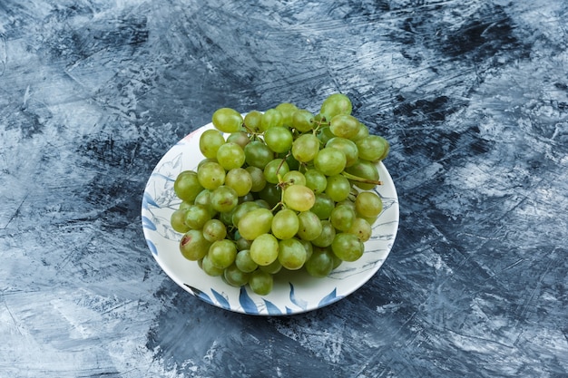 Green grapes in a plate on a grungy plaster background. high angle view.