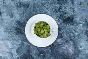 Foto gratuita uva verde in una tazza bianca con vista dall'alto piatto su uno sfondo di gesso grungy