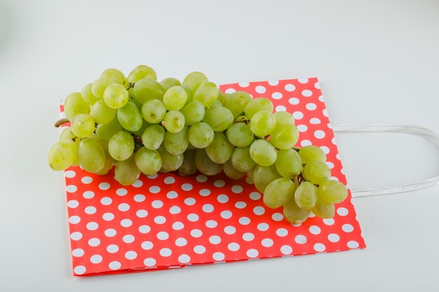 Green grapes on white and paper bag. high angle view.