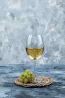 無料写真 汚れた石膏と枝編み細工品のプレースマットの背景にワインの側面図のガラスと緑のブドウ