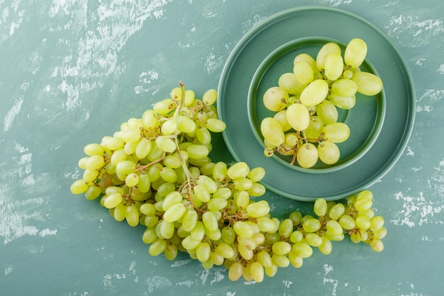 Green grapes with plate in a saucer on plaster,