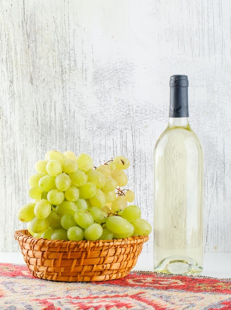 Green grapes with wine, kilim rug in a basket on white and grungy,