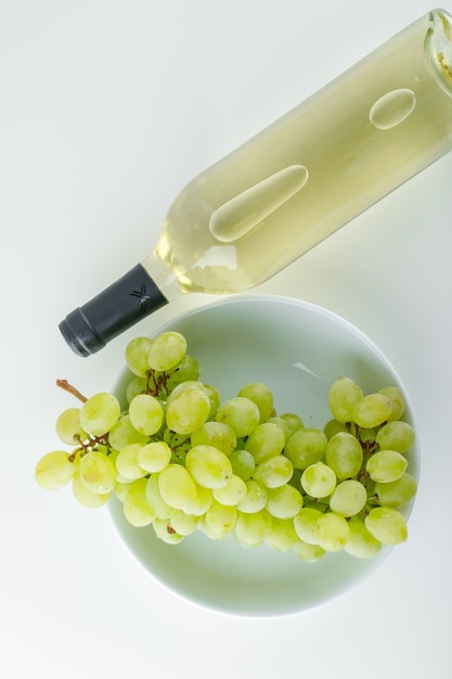 Green grapes with wine in a plate on white,