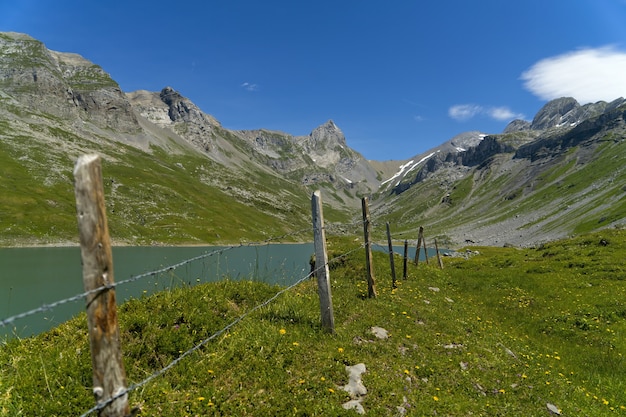 Foto gratuita campo di erba verde vicino alla montagna sotto il cielo blu durante il giorno