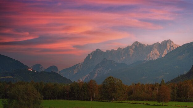 Green grass field near mountain under cloudy sky during daytime