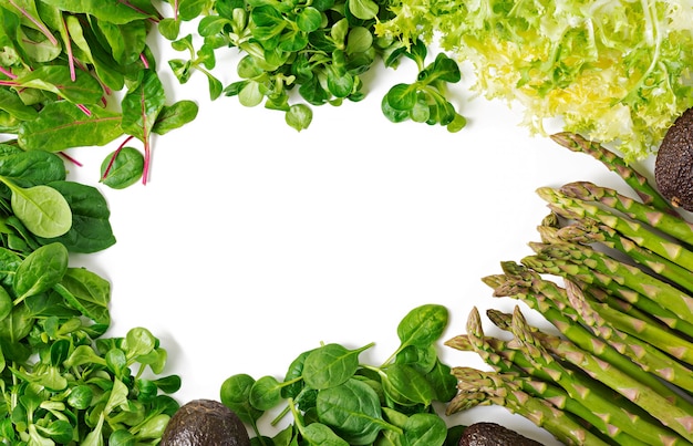 Green herbs, asparagus and black avocado on a white  background. Top view. Flat lay