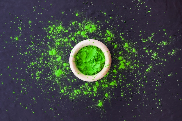 Зеленый холи порошок в миске на текстурированном фоне