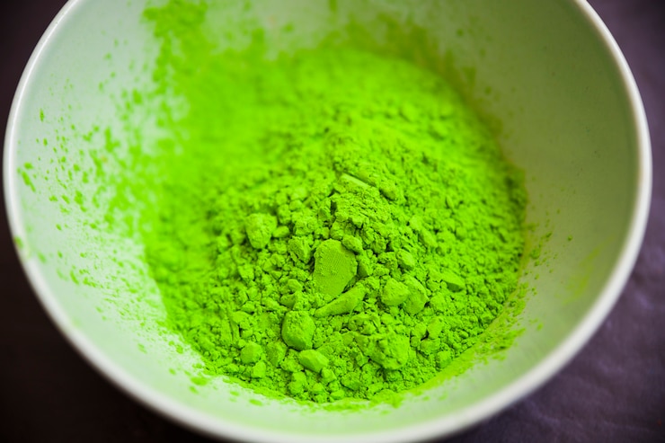 Free Photo green holi powder inside the white bowl on black backdrop