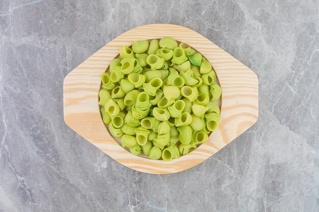 Green homemade pastas in a round wooden platter