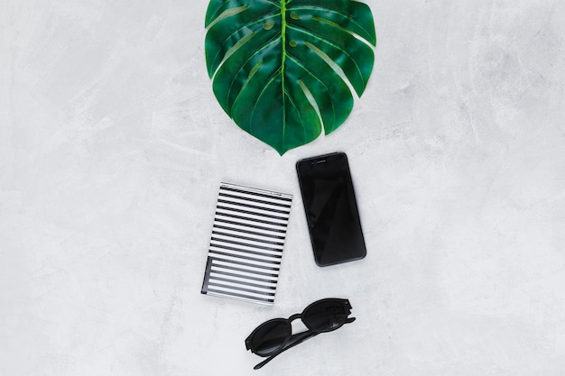 無料写真 平らな背景に緑の葉、サングラス、財布、スマートフォン