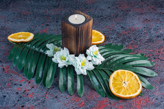 Free photo a green leaf with candle and sliced dried orange fruit on gray