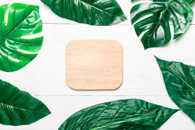 Green leaves around blank wooden board