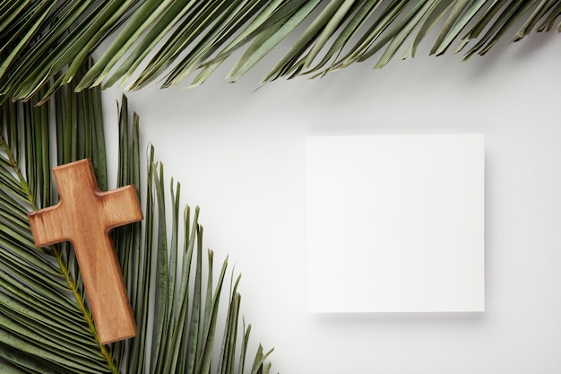 Free photo green leaves and cross arrangement flat lay