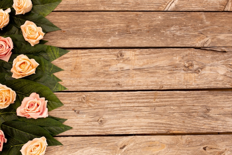 Free Photo green leaves and roses on wood background with copy space.
