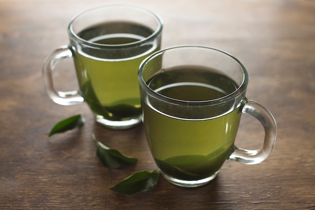 Free photo green lemon herbal tea cups on wooden desk