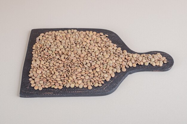 Green lentil beans on a black wooden board.