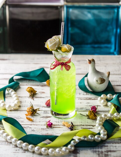 Green lime lemonadr in a glass jar on a wooden table.