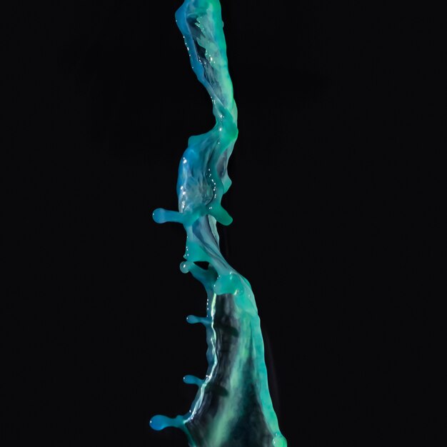 Green liquid falling on black backdrop