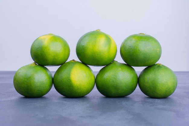 Green mandarin oranges on blue.