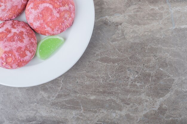 大理石の表面の大皿に緑のマーマレードとピンクのクッキー