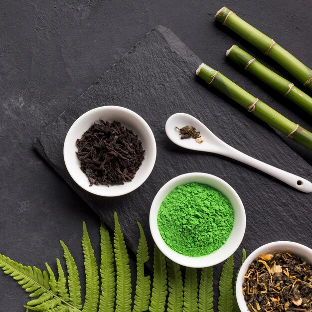 Зеленый чай матча и сухой чай с бамбуковой палочкой на черном фоне