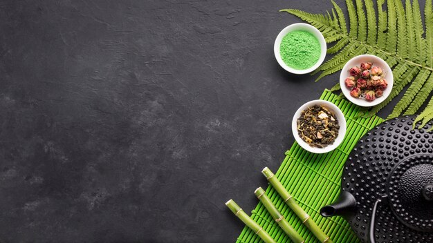 Green matcha tea powder and bamboo stick with copy space black background