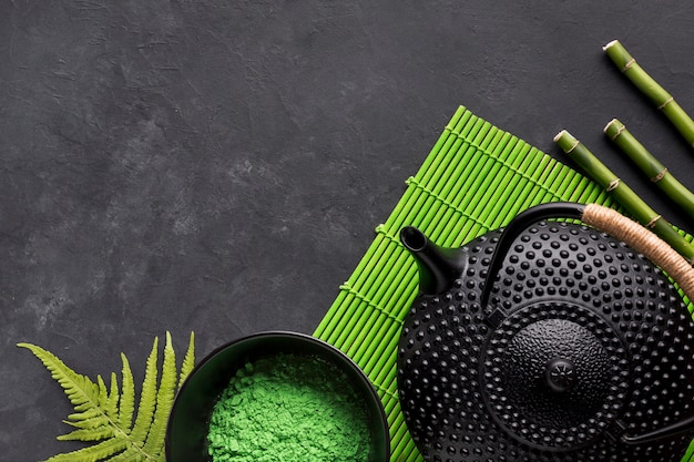 Polvere di tè verde matcha e teiera nera su tovaglietta