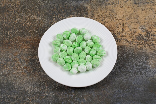 Зеленые ментоловые конфеты на белой тарелке.