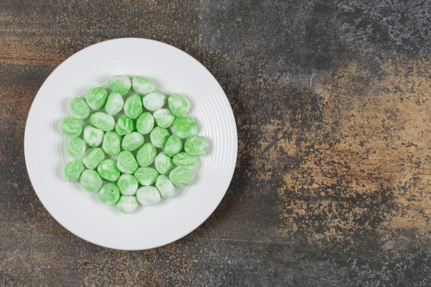 Green menthol candies on white plate.