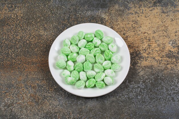 Green menthol candies on white plate.