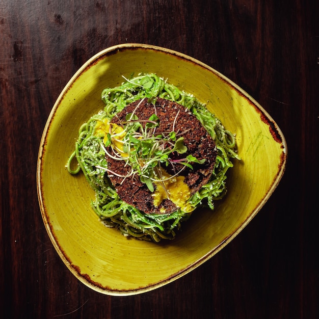 Foto gratuita tagliatelle verdi con una pagnotta di pane dietetico in cima