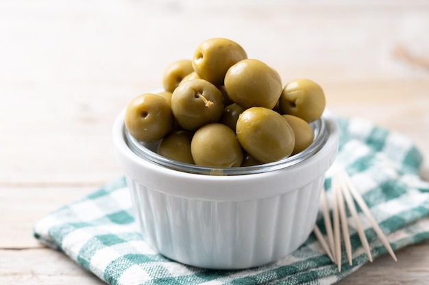 Free photo green olives in a bowl on wooden table