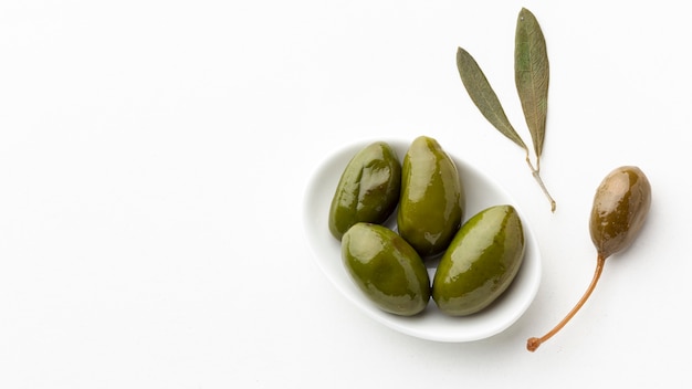 Green olives on plate with leaves with copy space