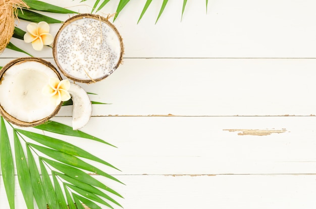 Green palm leaves with coconuts on wooden table