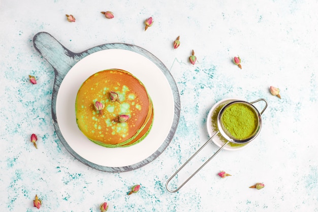 Green pancakes with matcha powder with red jam, top view