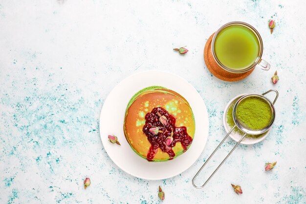Green pancakes with matcha powder with red jam, top view