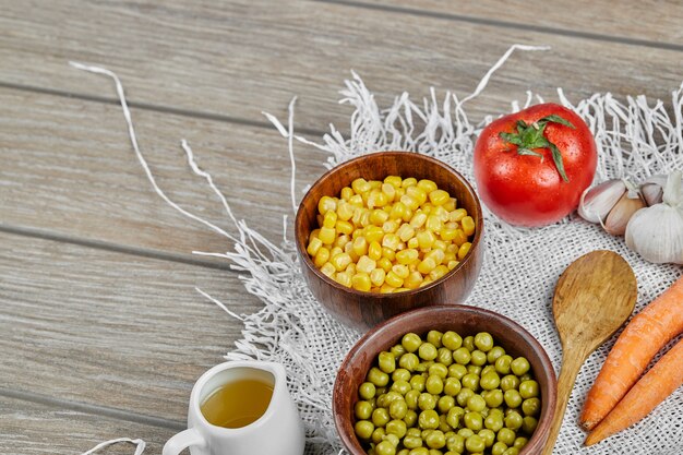 Green pea beans and corns in wooden cups . 