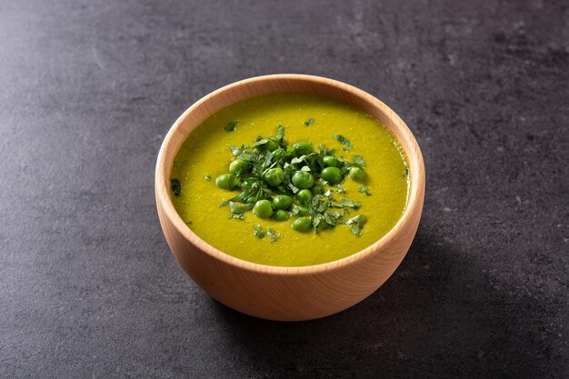 Green pea soup in a bowl on black slate background