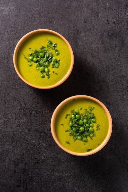 Green pea soup in a bowl on black slate background