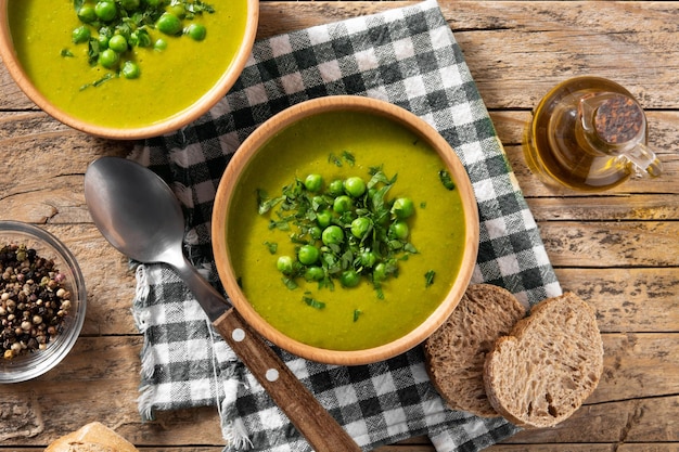 Green pea soup in a bowl on rustic wooden table Top view
